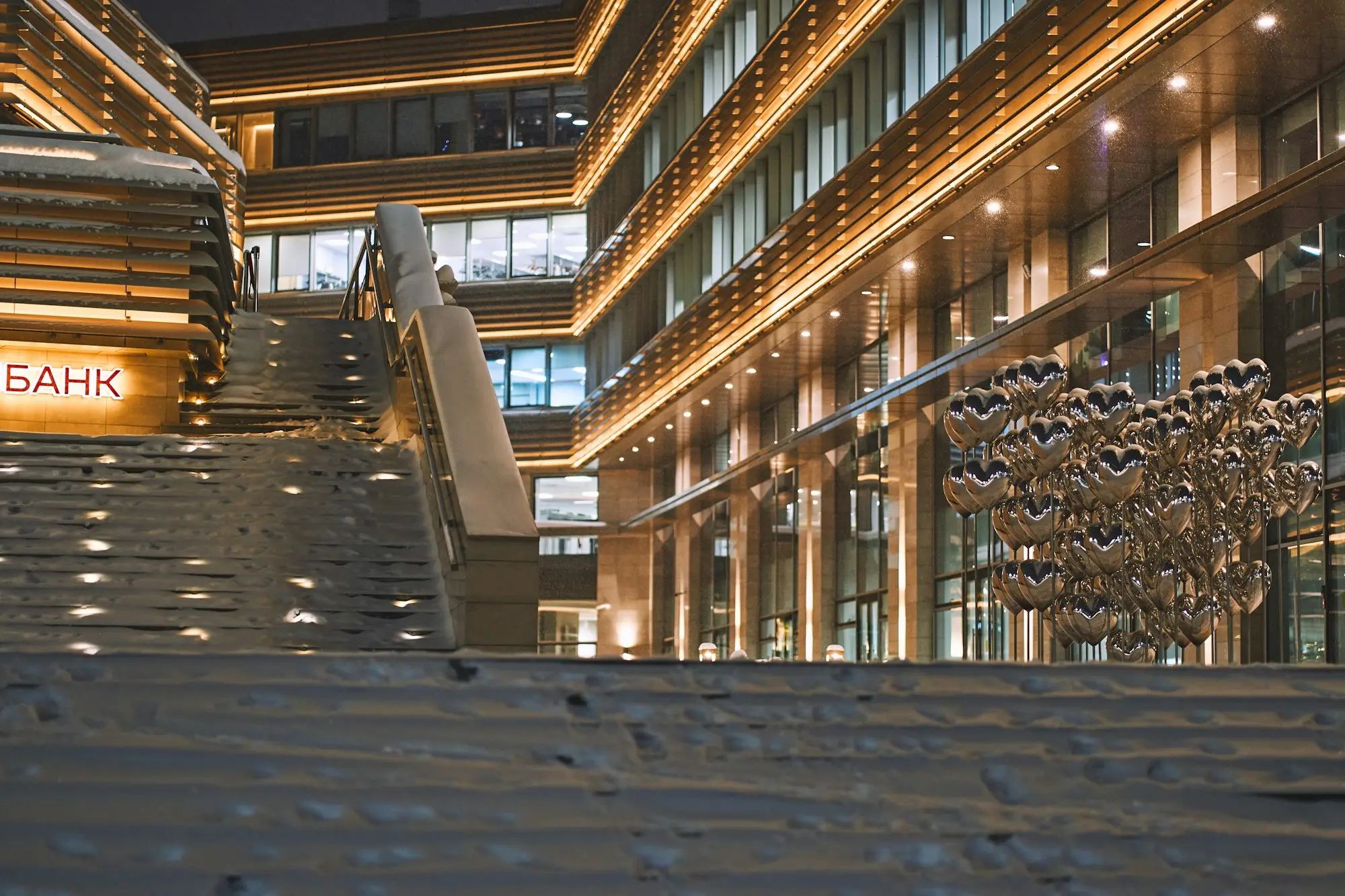 Modern office and bank buildings lit up at night with stairs leading to the entrance