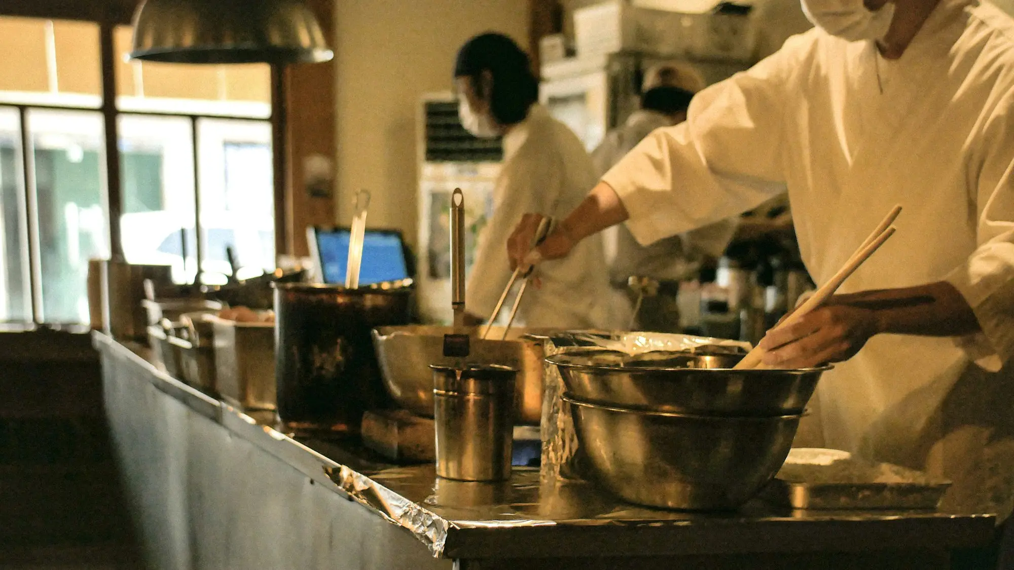 Chef cooking at the pass in a busy commercial restaurant kitchen