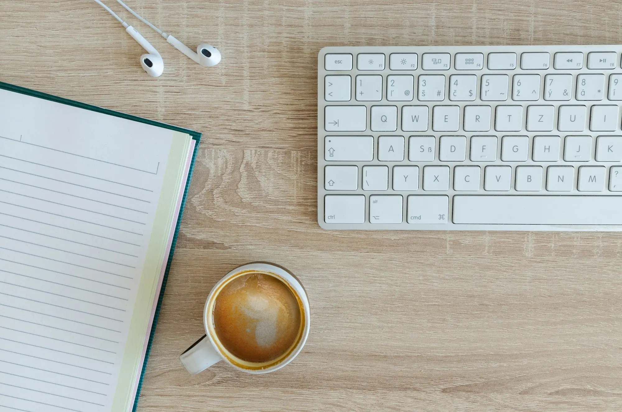 Coffee latte beside a keyboard on a desk while an owner plans the week's finances