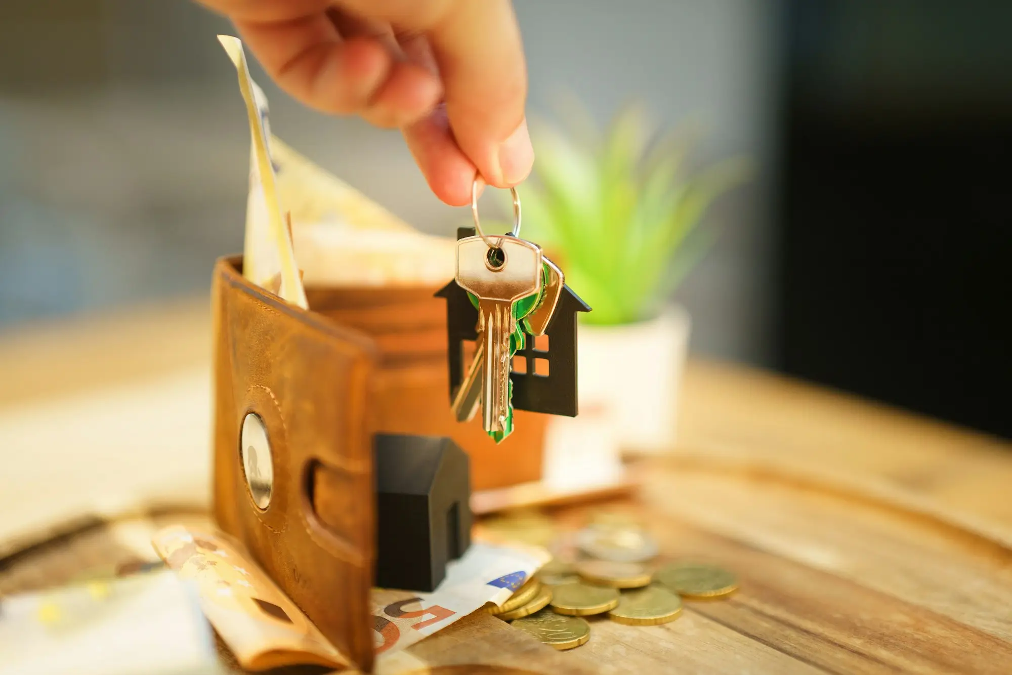 Hand holding a set of house keys and a wallet, representing property used as loan security