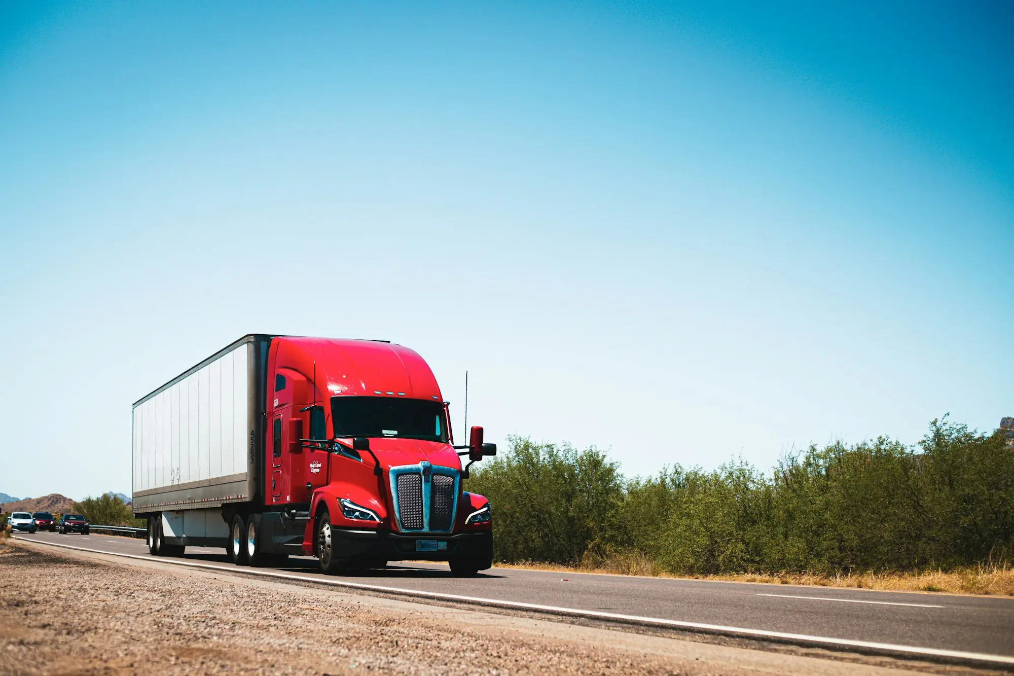 Red prime mover hauling freight along a country highway